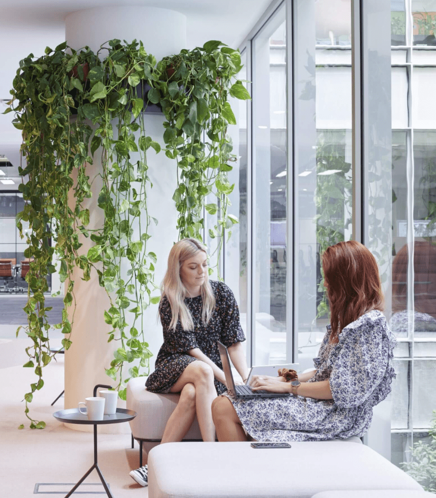 Two women sitting in a space with lots of plants